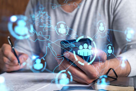 Double exposure of man signing contract with phone and social network icon hologram. Concept of...
