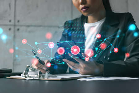 Businesswoman taking notes and abstract tech icons hologram. Double exposure. Technology security network solution concept.の写真素材