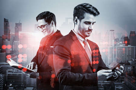 Two handsome young SMM specialists working on social media marketing strategy to achieve business goals. Hologram icons over Bangkok background.の写真素材