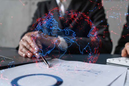 Man and woman working together on international business project. Blue infographic hologram of planet earth. World map. Multiexposure.の写真素材
