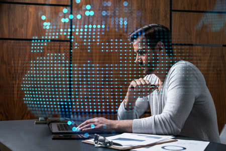 A serious caucasian manager in casual wears, using laptop to develop a new worldwide supply chain....