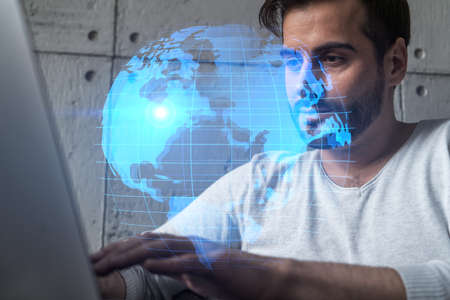A serious caucasian manager in casual wears, using laptop to develop a new worldwide supply chain....