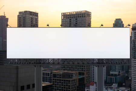 Blank white road billboard with Bangkok cityscape background at sunset. Street advertising poster, mock up, 3D rendering. Front view. The concept of marketing communication to promote or sell idea.の写真素材