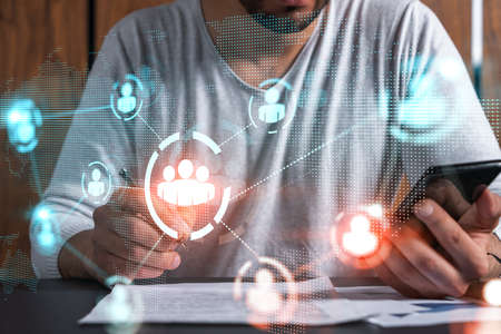 Double exposure of man signing contract with phone and social network icon hologram. Concept of...