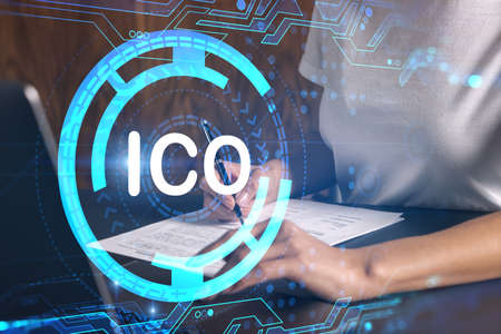 Businesswoman typing on computer in office. ICO icon hologram. Double exposure.