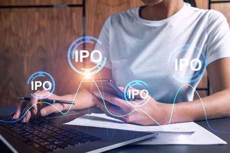 Businesswoman typing on computer in office. IPO icon hologram. Double exposure.