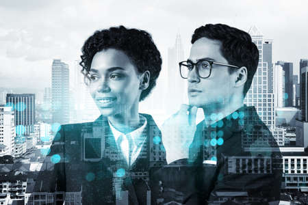 Businessman and businesswoman as a SMM specialists thinking about development of social media marketing strategy to achieve business goals. Hologram icons over Kuala Lumpur background.の写真素材