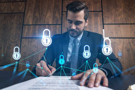 Businessman in office signs contract and lock hologram. Double exposure. Formal wear. Concept of safe data.の写真素材