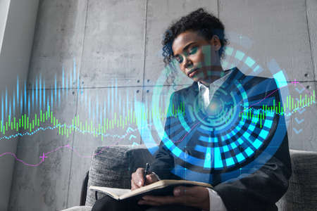Businesswoman taking notes and financial graph hologram. Double exposure. Business technology online...