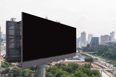 Blank black road billboard with Kuala Lumpur cityscape background at day time. Street advertising poster, mock up, 3D rendering. Side view. The concept of marketing communication.の写真素材