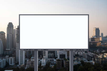 Blank white road billboard with Bangkok cityscape background at sunset. Street advertising poster, mock up, 3D rendering. Front view. The concept of marketing communication to promote or sell idea.の写真素材