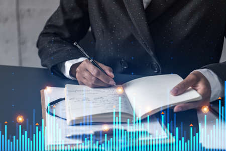 Financial market chart hologram and a woman taking notes. Business education and analysis concept....
