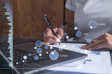 A client in casual wear is signing the contract to invest money in stock market. Internet trading and wealth management. Forex and financial hologram chart over the desk. Women in business concept.の写真素材
