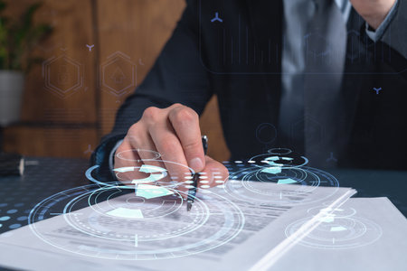 A client in dark blue suit is signing a contract to create a new software to present it in start up conference and gain investments to create a product. Technological graph over the desk.の写真素材