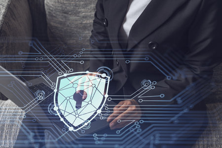 A woman programmer is typing a code on computer to protect a cyber security from hacker attacks and save clients confidential data. Padlock Hologram icons over the typing hands. Formal wear.の写真素材