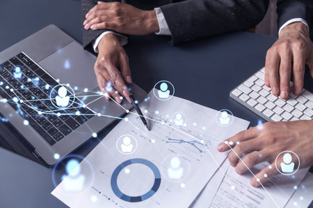 Two HR specialists man and woman analyzing the market of alumni to boost the intern program at international consulting company. Hiring new talented officers. Social media hologram icons.の写真素材