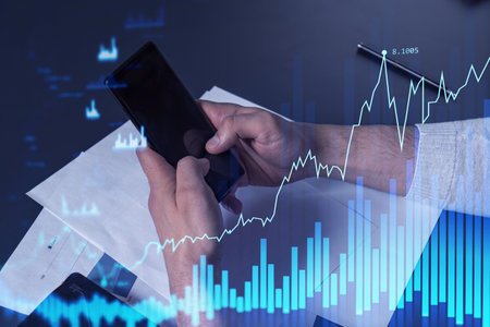 Trader holding in the hands a smart phone and researching stock market to proceed right investment...
