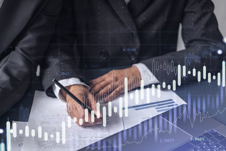 Two traders researching historic data to predict stock market behavior. Women in trading business concept. Forex and financial hologram chart over the table with the document.の写真素材