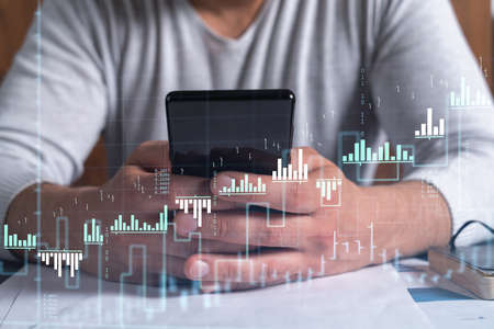 Trader holding in the hands a smart phone and researching stock market to proceed right investment...