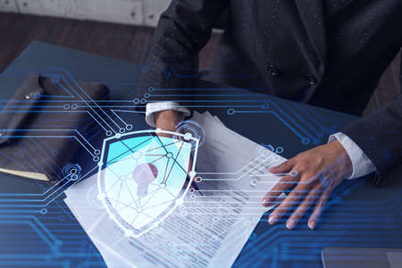 African American businesswoman in formal wear signing the contract to prevent probability of risks in cyber security. Padlock Hologram icons over the working desk. Women in business concept.の写真素材