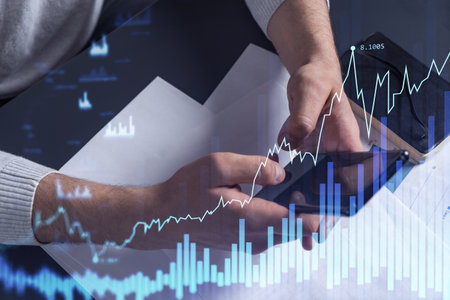 Trader holding in the hands a smart phone and researching stock market to proceed right investment...
