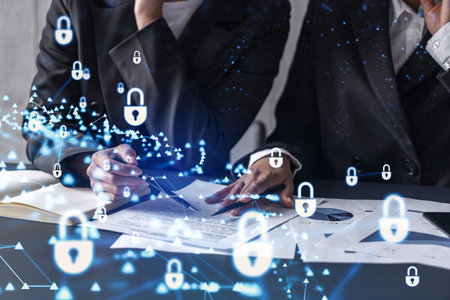 Two businesswomen working on the project to protect cyber security of international company. Padlock Hologram icons over the table with documents.の写真素材