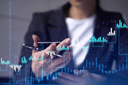 A woman trader holding in the hands a smart phone and researching stock market to proceed right...