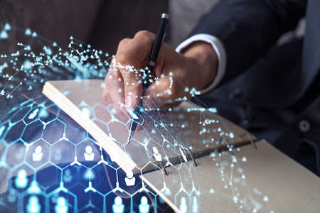HR specialist is taking notes concerning new candidates to create international network in recruitment process. Concept of success. Social media hologram icons. Formal suitの写真素材