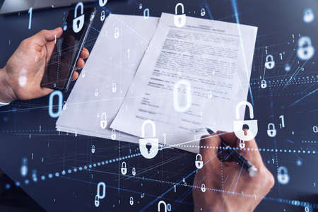 A businessman in formal wear signing the contract to prevent probability of risks in cyber security. Padlock Hologram icons over the working desk.の写真素材
