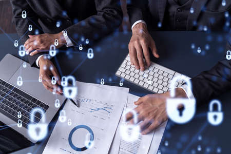Two businesspeople man and woman working on the project to protect cyber security of international company. Padlock Hologram icons over the table with documents. Formal wear. Workspace.の写真素材