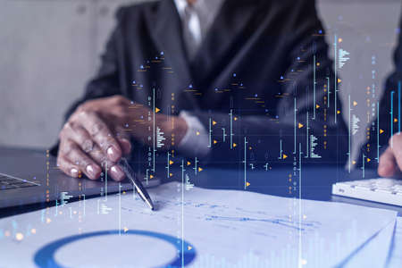 Two traders man and woman researching historic data to predict stock market behavior. Internet trading concept. Forex and financial hologram chart over the table with the documentsの写真素材