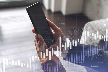 A woman trader holding in the hands a smart phone and researching stock market to proceed right...