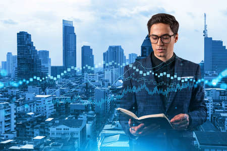 A young eastern handsome trader in suit examine his notes to predict the market behavior based on...
