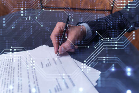 A client in dark blue suit is signing a contract to create a new software to present it in start up conference and gain investments to create a product. Technological graph over the desk.の写真素材