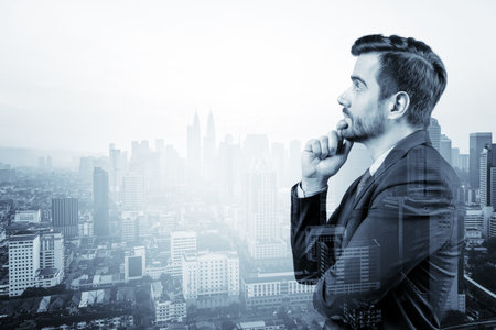 Young handsome businessman in suit with hand on chin thinking how to succeed, new career opportunities, MBA. Kuala Lumpur on background. Double exposure.の写真素材