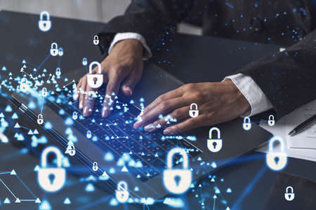A woman programmer is typing a code on computer to protect a cyber security from hacker attacks and save clients confidential data. Padlock Hologram icons over the typing hands. Formal wear.の写真素材