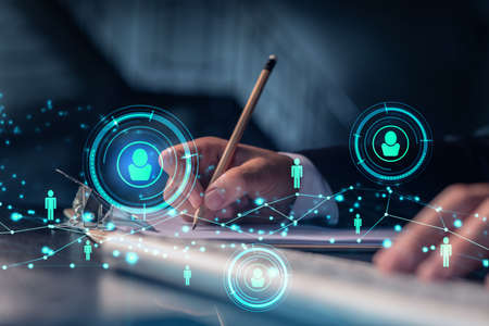 HR specialist is taking notes concerning new candidates to create international network in recruitment process. Concept of success. Social media hologram icons. Formal suitの写真素材