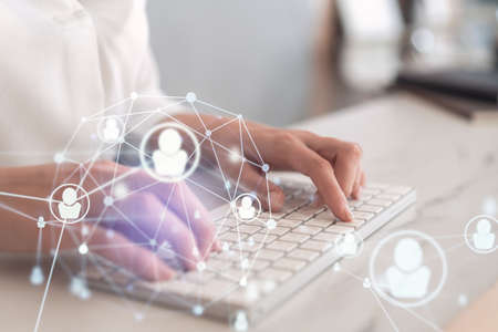 HR woman specialist is typing the keyboard in the internet to find the best candidates to create international network in recruitment process. Formal wear. Social media hologram icons.の写真素材