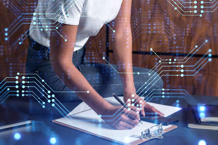 A businesswoman in casual wear writing down some ideas using phone to create innovative software to provide a completely new high-tech service. Close up shot. Hologram tech graphs. Concept of Dev teamの写真素材