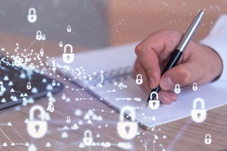 A programmer is taking notes of clients needs to protect cyber security from hacker attacks and save clients confidential data. Padlock Hologram icons over the typing hands. Formal wearの写真素材