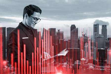 A young eastern handsome trader in suit examine his notes to predict the market behavior based on...