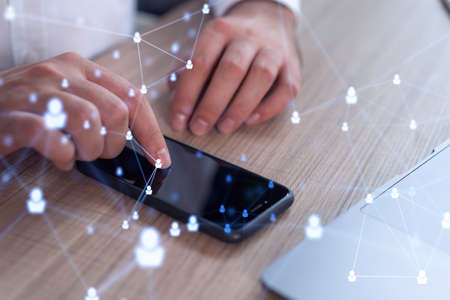 Hands of hr specialist browsing social networks in the Internet in smart phone to find the best candidates to hire international team. Concept of success. Media hologram icons. Formal wear.の写真素材