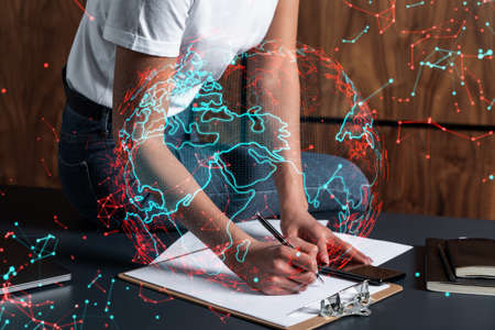 Businesswoman taking notes using smart-phone. World map hologram double exposure.の写真素材