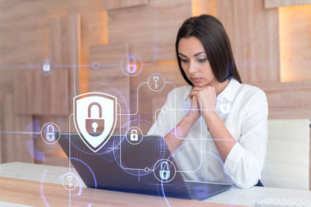 Attractive businesswoman in white shirt at workplace working with laptop to defend customer cyber...