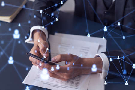 A potential employee in formal wear reading the contract to boost his career and gain new opportunities in personal growth. Checking the details of the deal at smartphone. Social media hologram iconsの写真素材