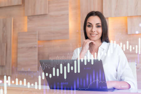 Attractive businesswoman in white shirt at workplace working with laptop to optimize trading...