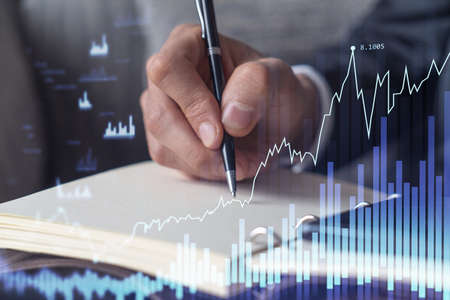 A trader in formal wear writing down some quotes to research stock market trends using smart phone...