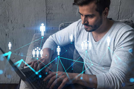A serious caucasian manager in casual wears, using laptop to develop a new network. Double exposure....