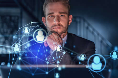 Portrait of handsome businessman in formal suit looking for employees and thinking how to hire new candidates for international business consulting. HR, networking icons. Hand on chinの写真素材