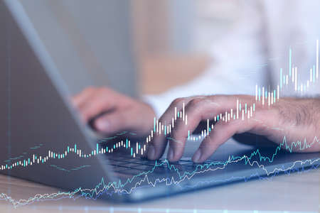 Hands typing the keyboard to research stock market to proceed right investment solutions. Internet...